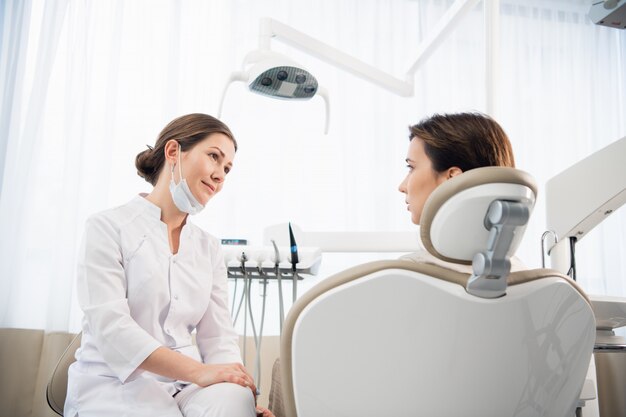 Uma jovem mulher explicando seu problema dentário ao seu médico que está ouvindo atentamente