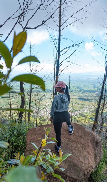 Uma jovem mulher hispânica de pé em uma rocha apreciando a bela natureza