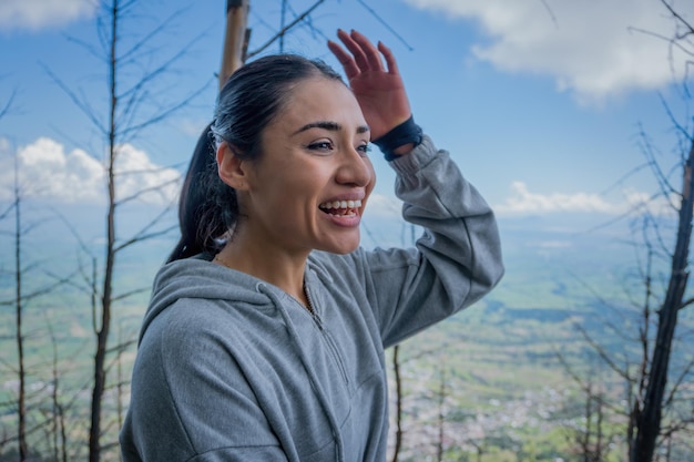 Uma jovem mulher hispânica sentada em uma rocha apreciando a beleza da natureza