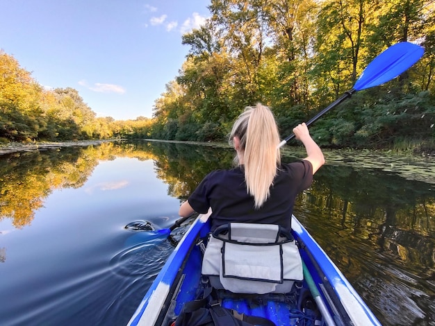 Foto uma jovem mulher loira está remando em um caiaque visão traseira turismo e recreação ao ar livre