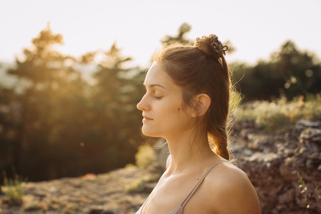 Uma jovem mulher medita na natureza em uma floresta de pinheiros ao pôr-do-sol estilo de vida saudável desfrutando da natureza