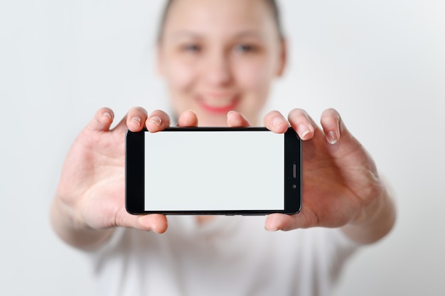 Foto uma jovem mulher segura o telefone horizontalmente com uma tela branca com um lugar para copyspace.