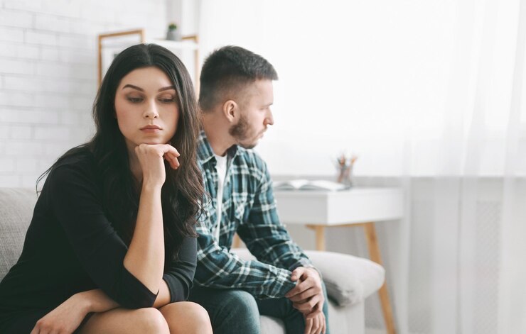 Foto uma jovem mulher senta-se em um sofá com uma expressão preocupada seu queixo descansando em sua mão ela usa um