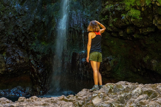 Uma jovem na cascata no final do trilho da cascata na Levada do Caldeirão Verde Queimadas Madeira