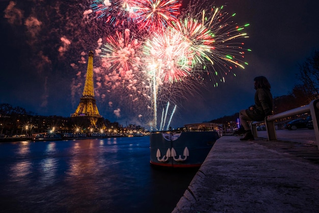 Uma jovem na cidade do amor desfrutando de uma queima de fogos ao lado do rio Sena em Paris França