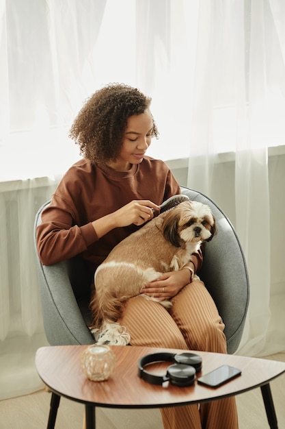 Foto uma jovem negra escovando um cachorrinho fofo em casa e cuidando de animais de estimação