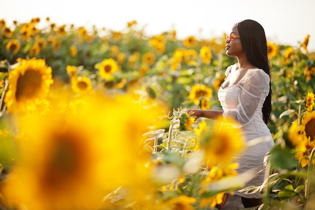 Uma jovem negra usa pose de vestido de verão em um campo de girassol