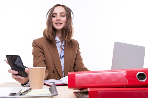 Uma jovem no local de trabalho Secretária do escritório com um telefone nas mãos sobre um fundo branco