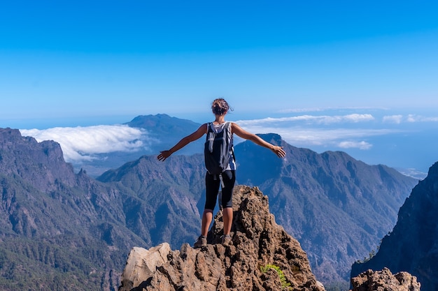 Uma jovem no topo do vulcão da Caldera de Taburiente perto de Roque de los Muchachos em uma tarde de verão de braços abertos, La Palma, nas Ilhas Canárias. Espanha