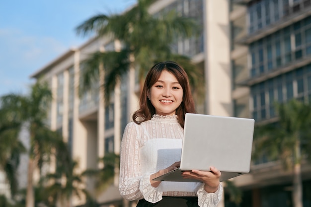 Uma jovem olha as informações em um laptop ao ar livre.