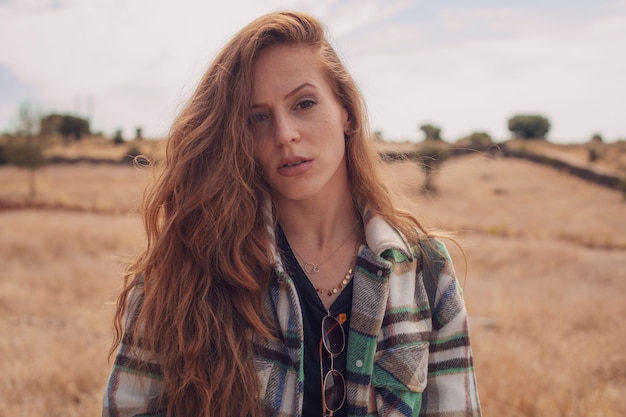 Foto uma jovem olhando para a câmera com um campo ao fundo