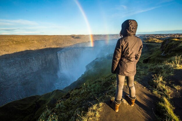 Uma jovem olhando para a Dettifoss Waterfall Islândia