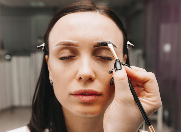 Uma jovem passa por um procedimento de correção de sobrancelha em um salão de beleza, a garota pinta as sobrancelhas no salão