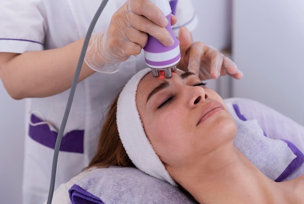 Uma jovem passando por um tratamento de lifting facial de radiofrequência facial Tratamento de cuidados com a pele facial antienvelhecimento rejuvenescimento facial Conceito de beleza e dermatologia