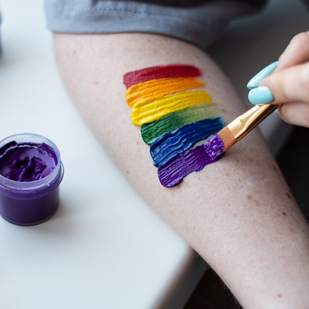 Foto uma jovem pinta um arco-íris na mão com cores brilhantes em sinal de solidariedade à comunidade lgbt