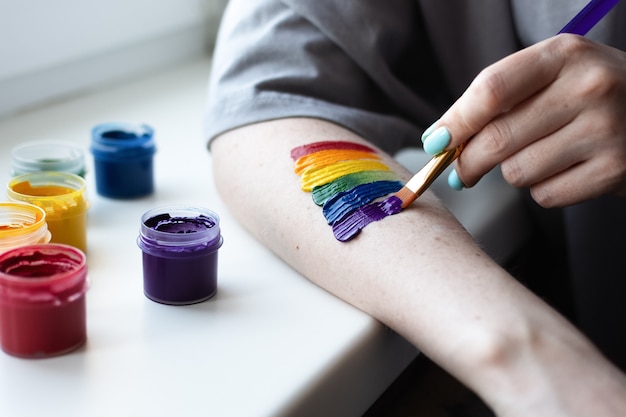 Uma jovem pinta um arco-íris na mão com cores brilhantes