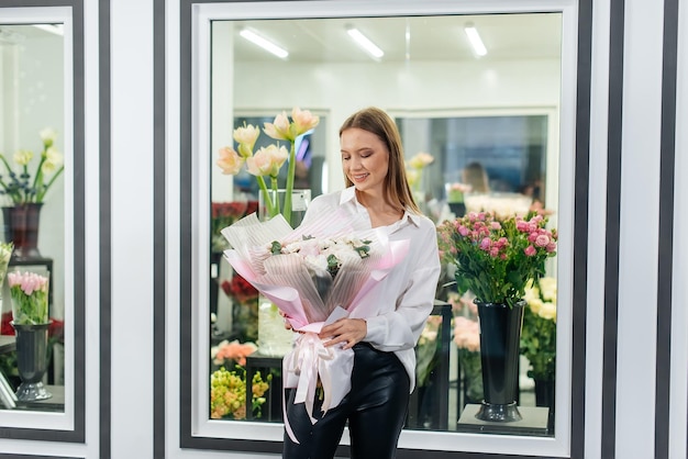 Uma jovem posa com um lindo buquê festivo no contexto de uma loja de flores aconchegante Floricultura e buquê em uma loja de flores Pequenas empresas