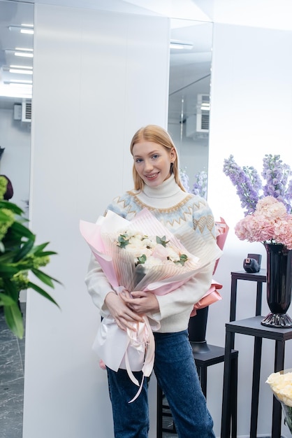 Uma jovem posa com um lindo buquê festivo no contexto de uma loja de flores aconchegante Floricultura e buquê em uma loja de flores Pequenas empresas