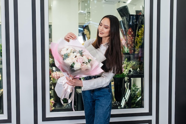 Uma jovem posa com um lindo buquê festivo no contexto de uma loja de flores aconchegante Floricultura e buquê em uma loja de flores Pequenas empresas