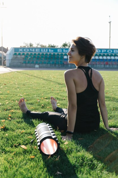 Foto uma jovem pratica esportes ao ar livre com um rolo para automassagem