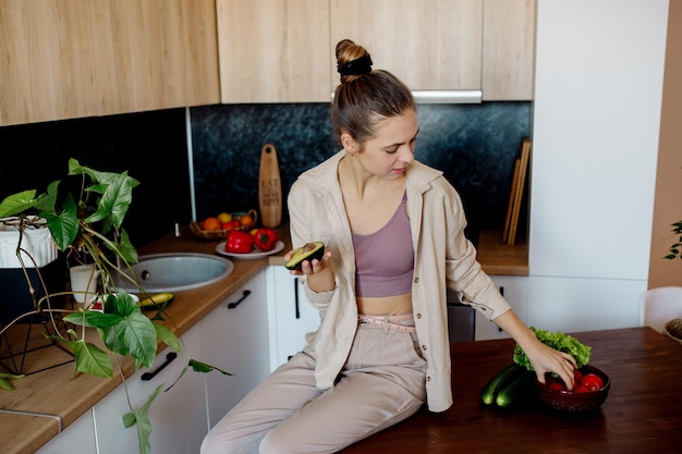 Uma jovem prepara salada de legumes em casa Cozinha vegana