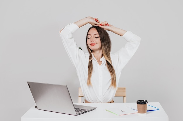 Foto uma jovem relaxa-se no seu local de trabalho isolada sobre um fundo branco.