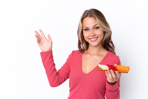 Uma jovem russa segurando um sashimi isolado no fundo branco, estendendo as mãos para o lado e convidando-o a vir