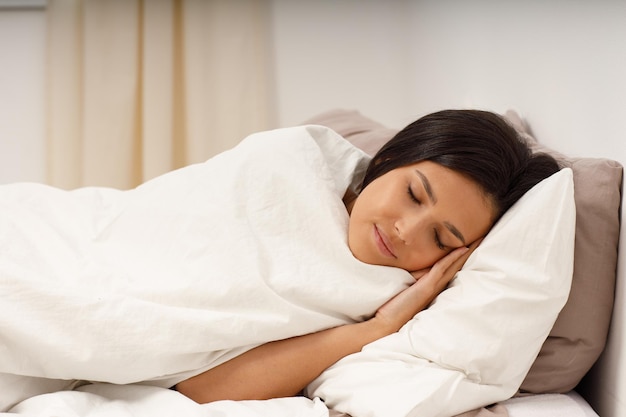 Foto uma jovem saudável cobre o cobertor dormindo com os olhos fechados na cama no quarto