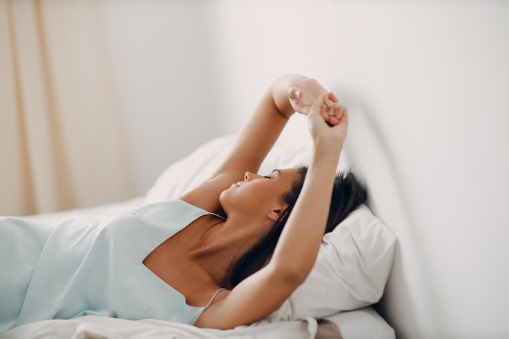 Foto uma jovem saudável vestindo camisola se estende deitada na cama no quarto
