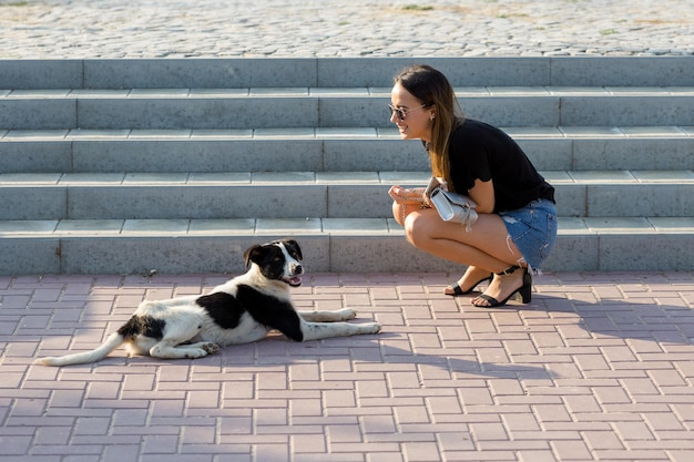 Uma jovem se senta em um banco em um parque e faz anotações Vestida em um estilo livre Mulher de negócios falando ao telefone com clientes