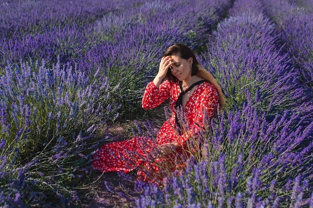 Uma jovem se senta em um campo de lavanda com um chapéu de palha pendurado no pescoço