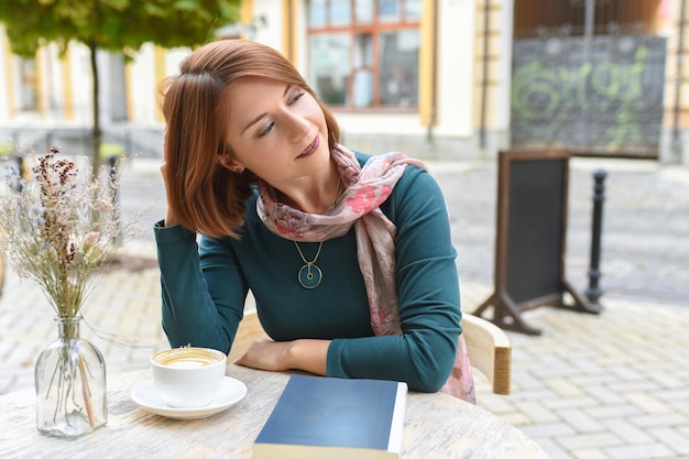 Uma jovem se senta em uma mesa em um café de verão