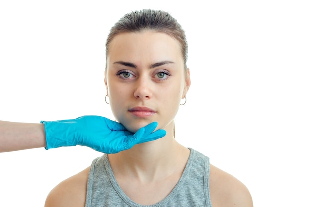 Uma jovem segurando o queixo em uma luva azul no salão de beleza está isolada em um fundo branco