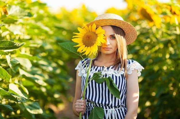 Uma jovem segurando um girassol em um campo florido de girassóis