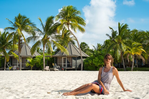 Foto uma jovem sentada em uma praia de areia branca