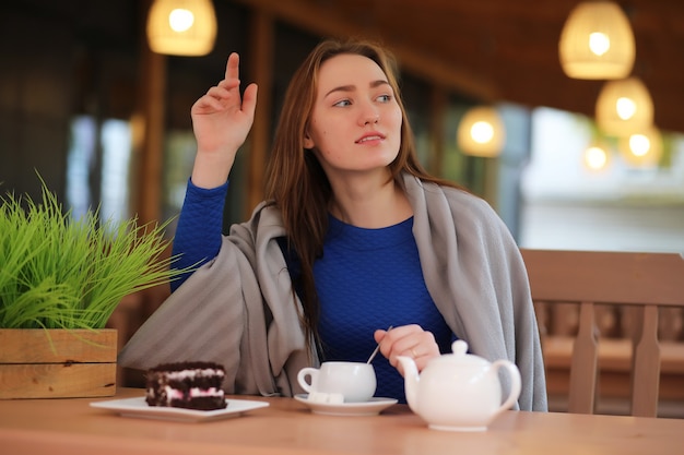 Foto uma jovem sentada num café a beber chá com sobremesa