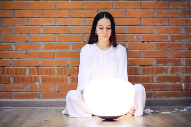 Uma jovem serena e relaxada em casa, feliz e calma, sonha com bem-estar respirando ar fresco em casa aconchegante