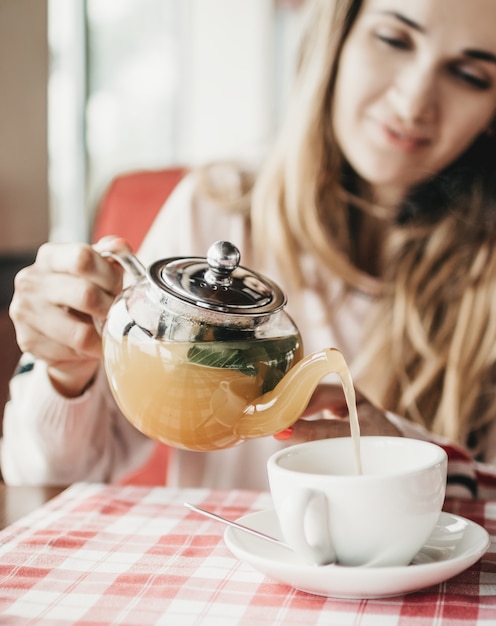 Foto uma jovem serve uma xícara de chá de frutas com hortelã em um café