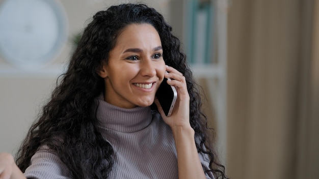 Uma jovem sorridente e muito árabe fala por telefone móvel, desfruta de uma conversa sem fio, conta fofocas