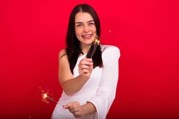 Uma jovem sorridente em um vestido com estrelinhas em um fundo vermelho olha para a câmera no estúdio