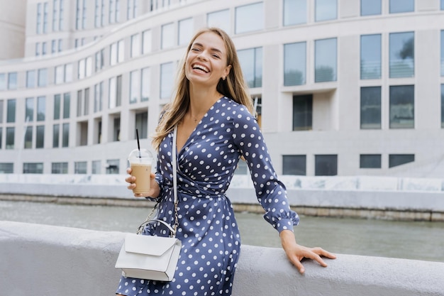 Uma jovem sorridente está bebendo café do lado de fora Retrato de verão de uma mulher em um vestido azul