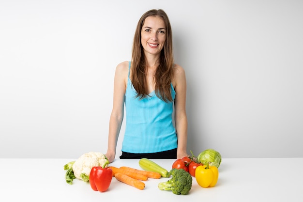 Foto uma jovem sorridente na cozinha legumes frescos estão sobre a mesa