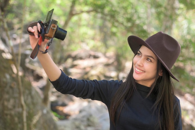 Uma jovem trekker tomando selfie com câmera nas férias da floresta e conceito de viagem