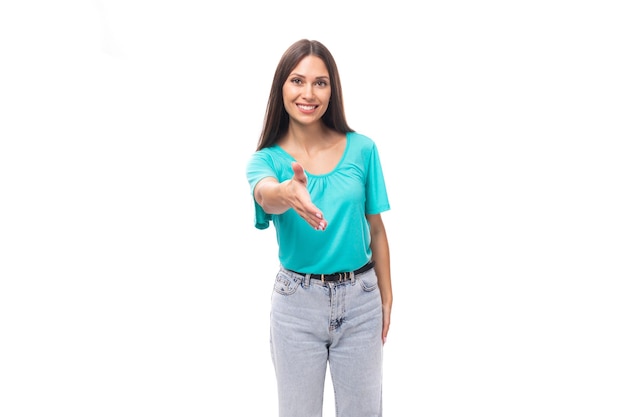 Uma jovem triste morena européia com cabelos lisos, vestida com uma camiseta azul, estende a mão para