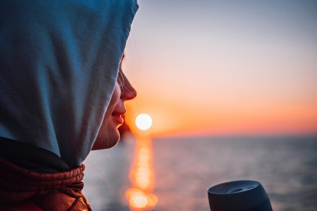 Uma jovem turista Mulher segurando um copo de café enquanto está sentado ao ar livre e apreciando o nascer do sol sobre a paisagem de montanha do mar Rotina de fitness yoga feminina Harmonia e meditação de estilo de vida saudável