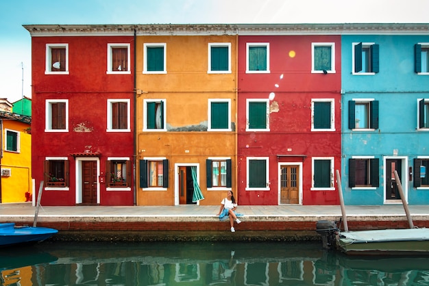 Foto uma jovem turista nas coloridas ruas de burano, em veneza, sorrindo e visitando a cidade italiana