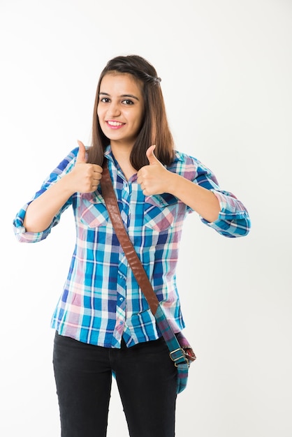 Foto uma jovem universitária muito indiana ou asiática segurando livros e bolsa enquanto está isolada sobre um fundo branco