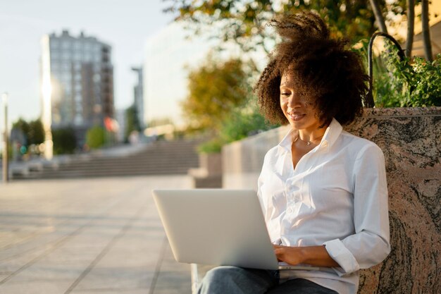 Foto uma jovem usa um laptop na rua para treinamento online