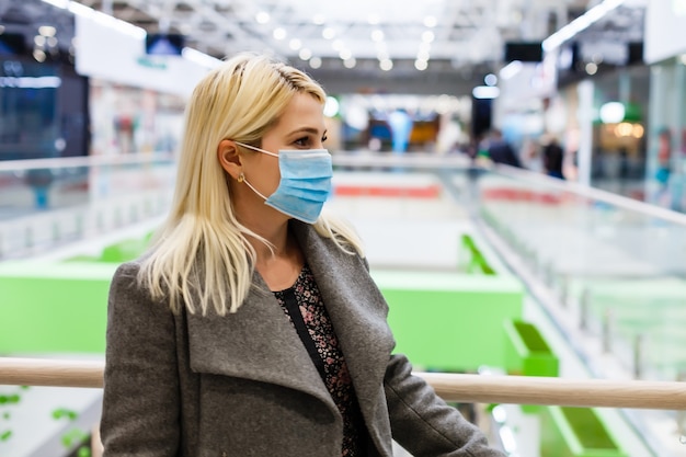 Uma jovem usa uma máscara protetora enquanto faz compras no shopping. o conceito de saúde contra doenças e proteção contra vírus.