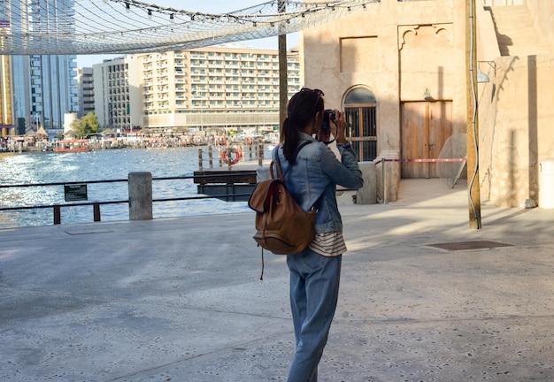 Uma jovem viajante com uma mochila nas costas caminha e fotografa as antigas ruas estreitas de